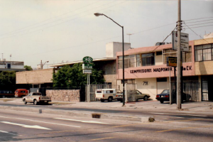 Fachada histórica de la sede antigua de Compresores Maqpower S.A. de C.V., con vehículos estacionados frente al edificio.